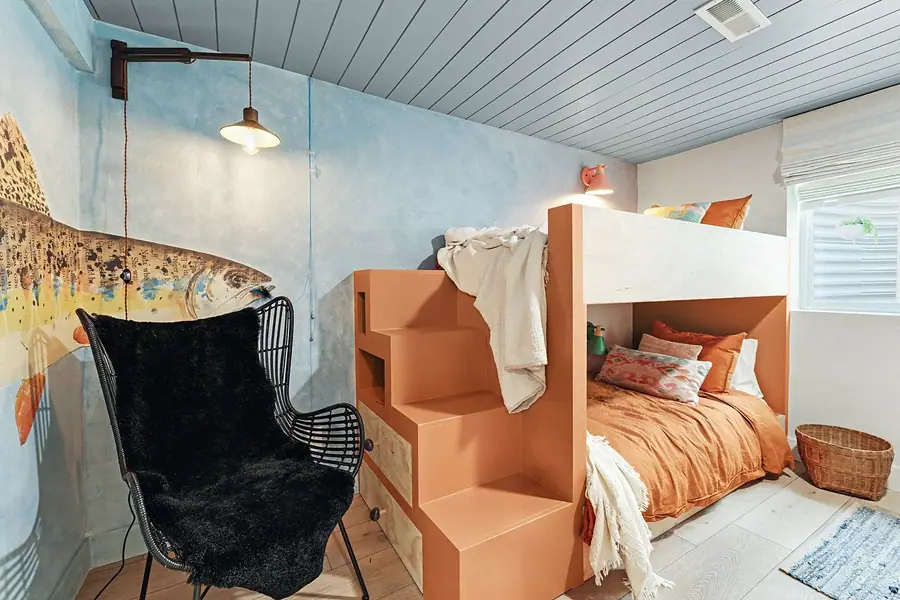 Midway kids bunk room with orange built-in beds, fish mural, and black rattan chair