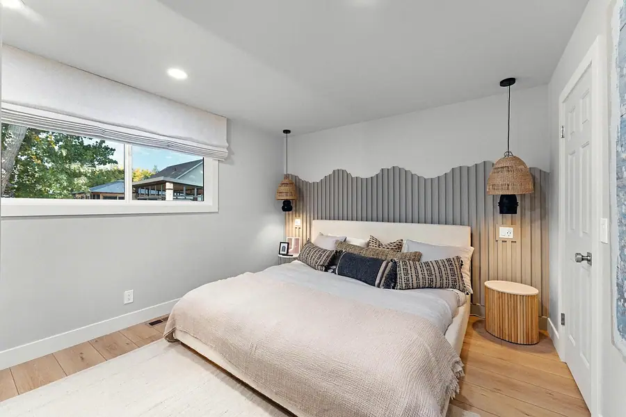 Midway bedroom with layered neutral bedding, textured headboard wall, and woven pendants