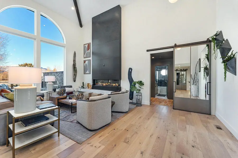 Great room with soaring arched windows, modern fireplace, and light oak floors