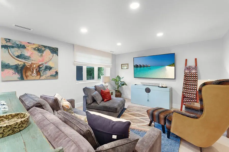 Elysium living room with gray sectional, mustard chair, and tropical TV art