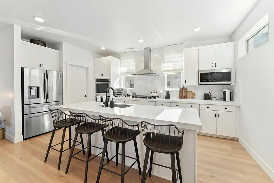 Silver Creek kitchen island with four dark stools and open white cabinetry