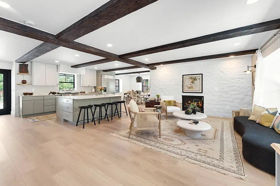 Little Gem open kitchen and living with sage cabinetry, beams, and fireplace