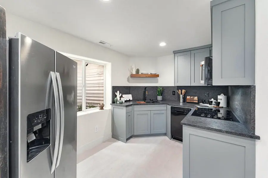 Lower-level kitchen with stainless refrigerator and gray cabinetry