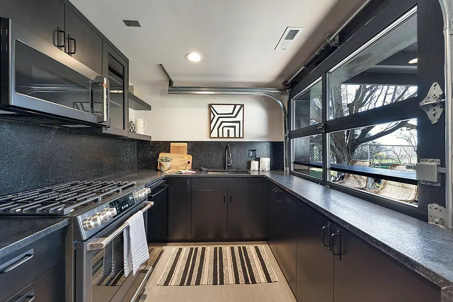 Fairway House chef kitchen with gas range, black counters, and outdoor views