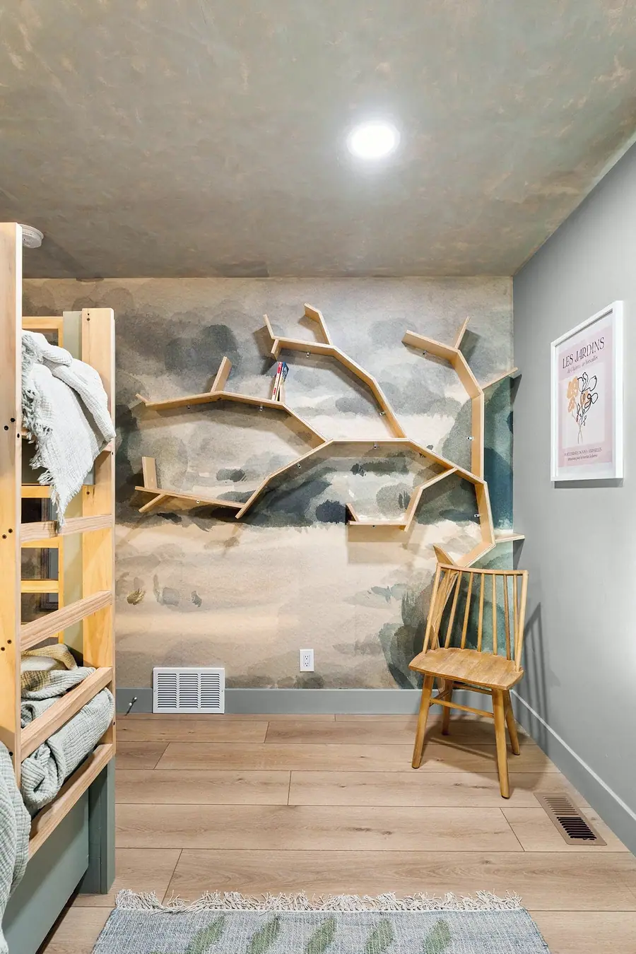Midway kids room with tree-branch shelves, landscape mural, and wooden bunk bed