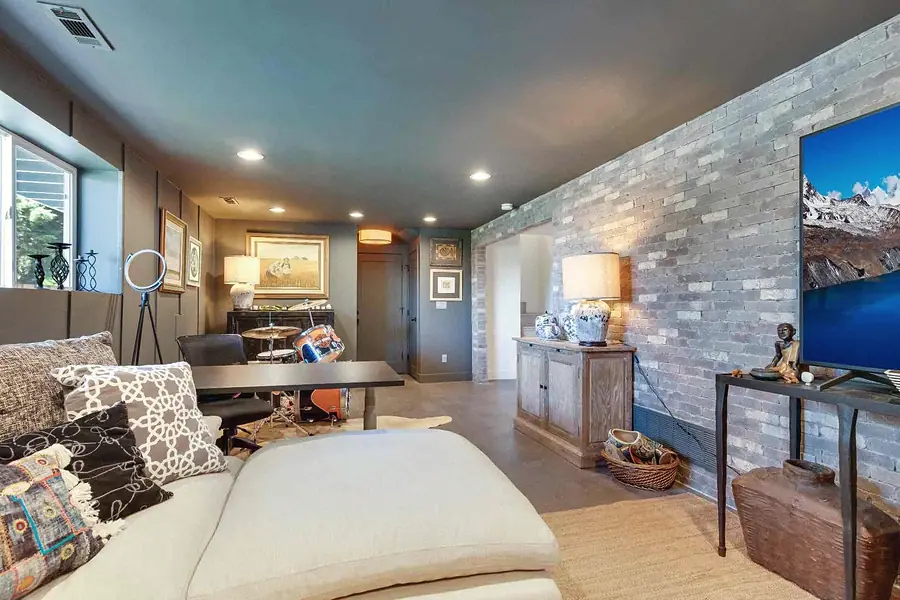 Wallace Project basement lounge with sofa, brick wall, and media console