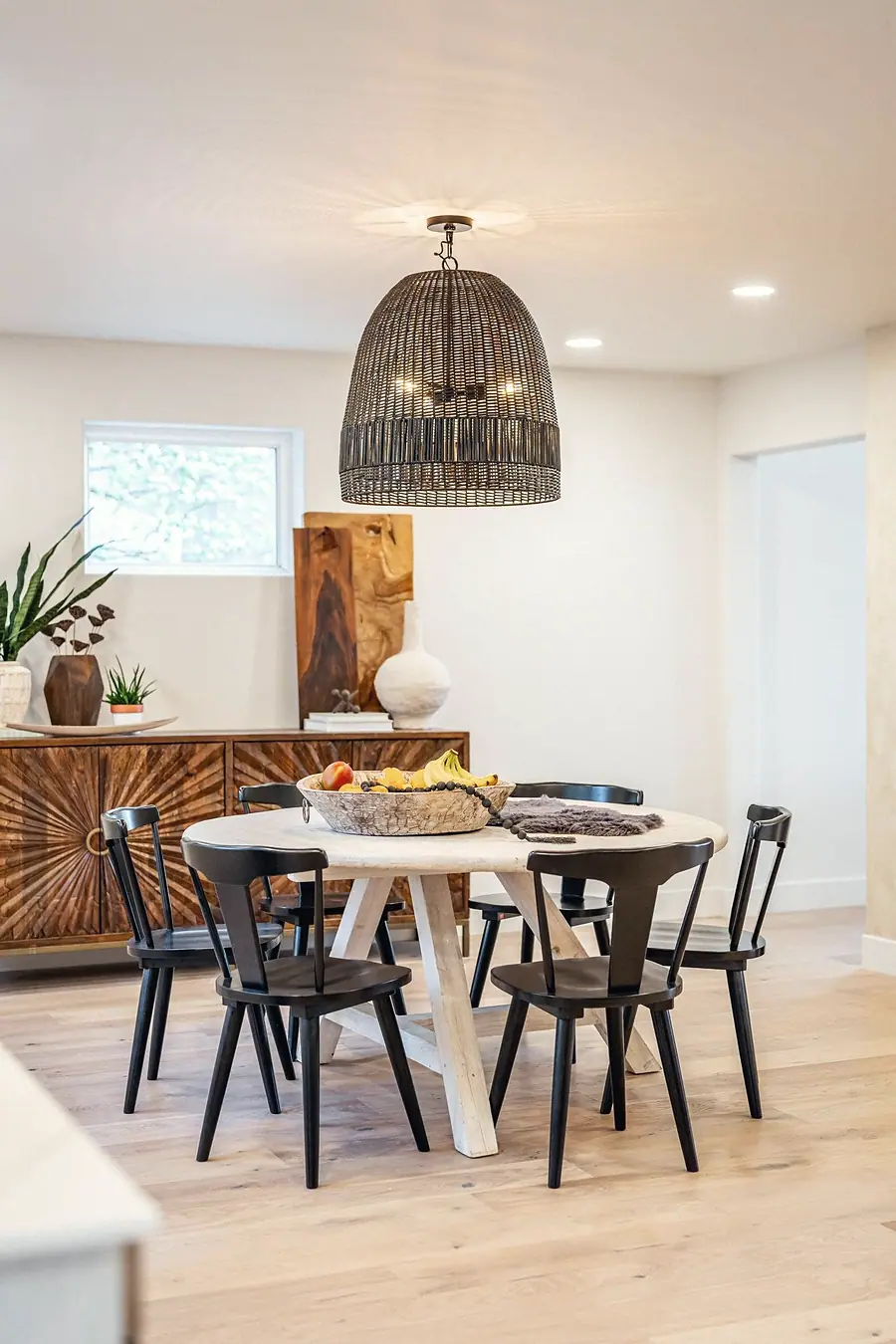 Grand Vista dining room with round table, woven pendant, and warm wood furnishings