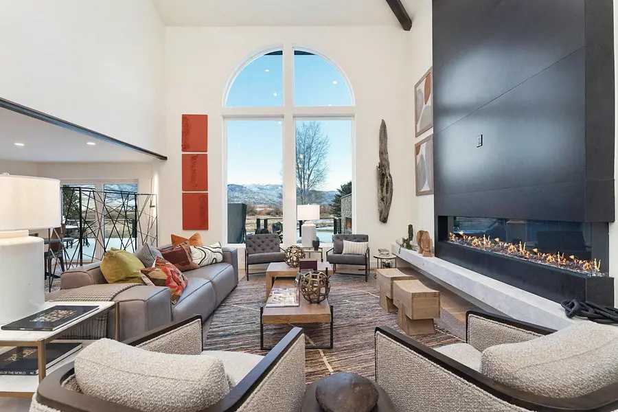 Living room seating around the fireplace with soaring arched windows