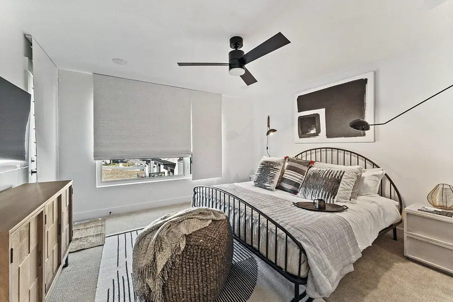 Silver Creek bedroom with black metal bed, woven pouf, and abstract wall art