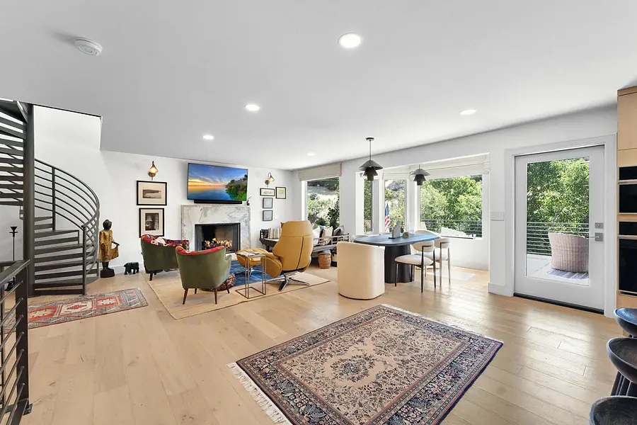 Elysium living and dining open plan with spiral stair, fireplace, and Persian rugs
