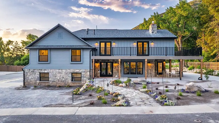 Little Gem front exterior with stone courtyard garden and mountain backdrop