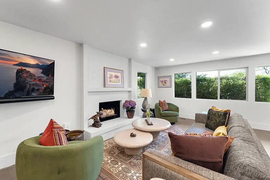 Crista da Montanha living room with white brick fireplace, green chairs, and garden windows