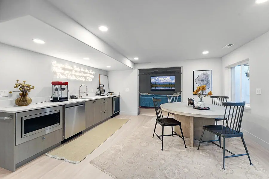 Grand Vista lower-level kitchenette, round dining table, and media room beyond