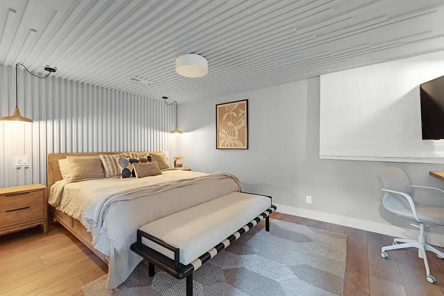 Midway primary bedroom with fluted ceiling, wood bed, and desk workspace