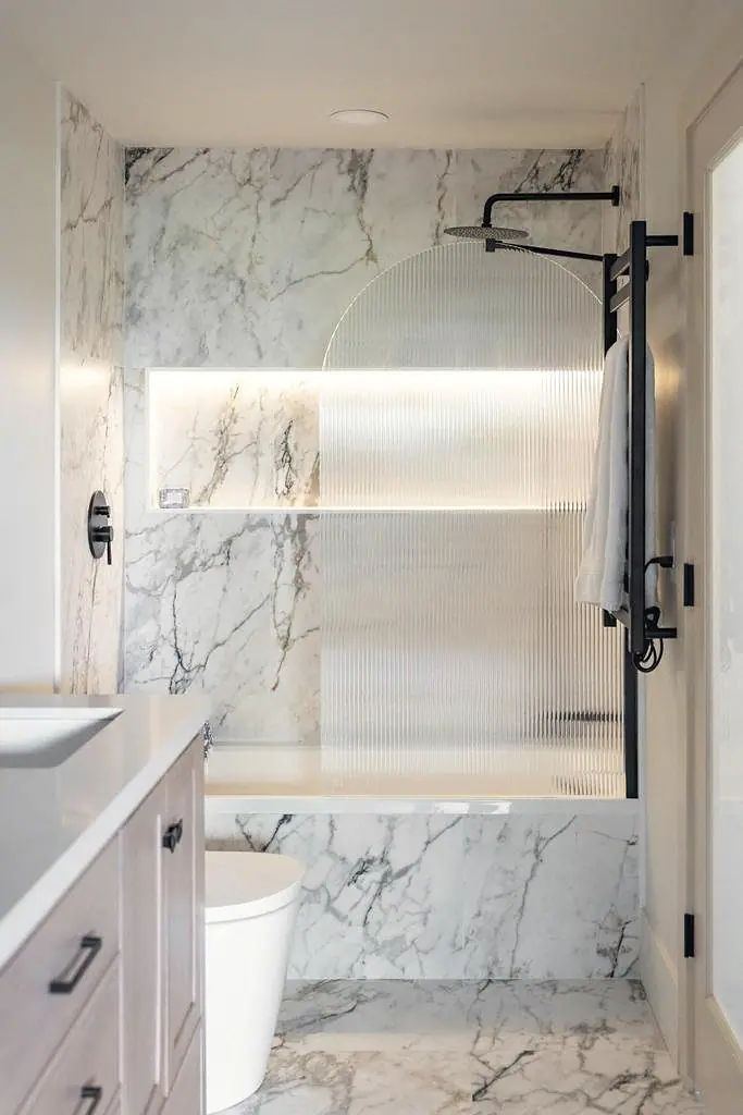 Crista da Montanha marble bath with fluted glass tub screen and black rain shower