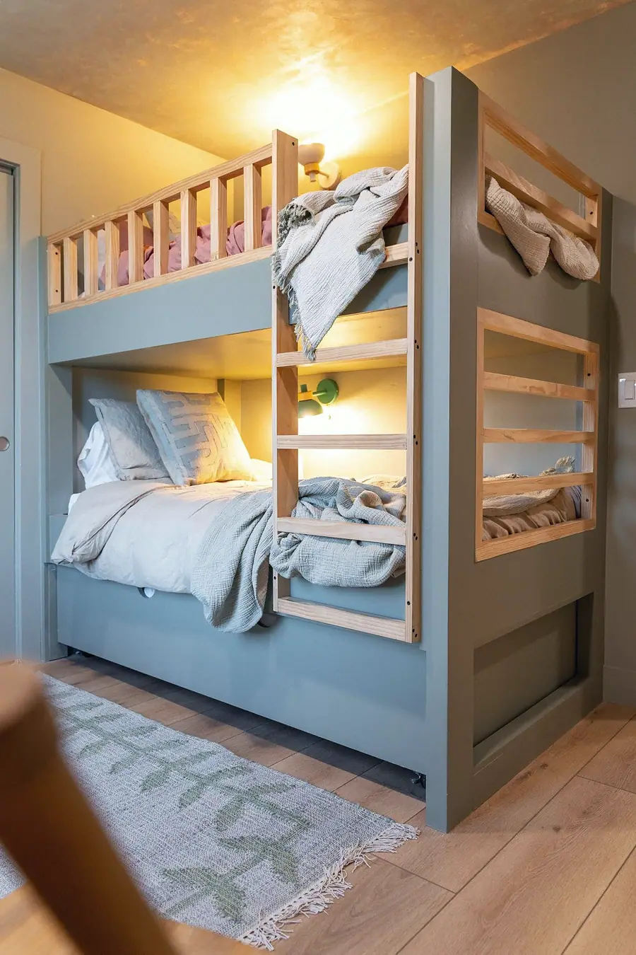 Midway sage-green built-in bunk beds with natural wood ladder and soft lighting