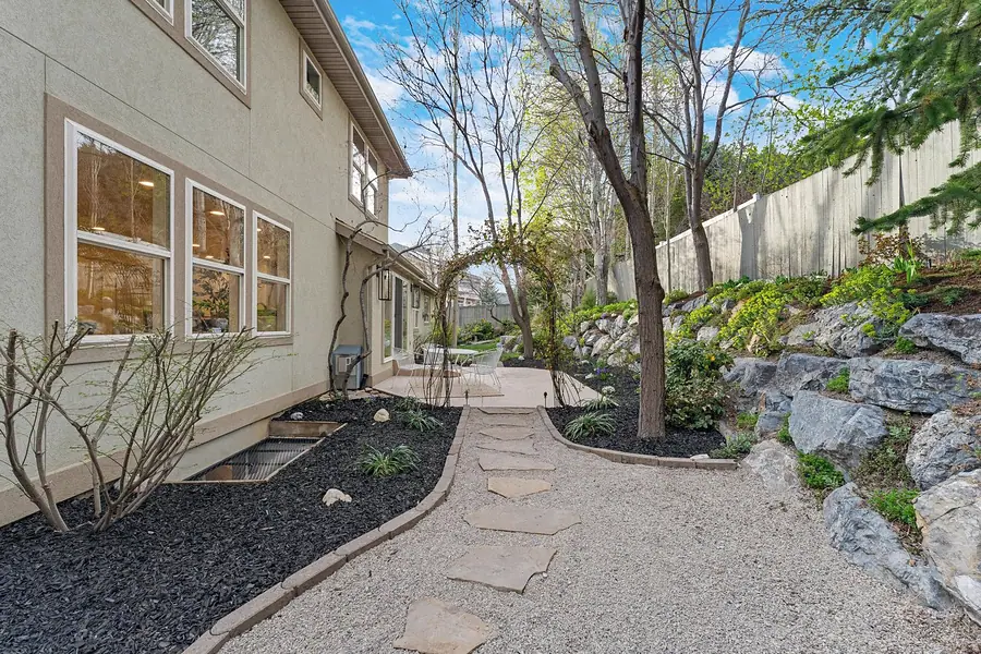 Grand Vista side garden path with gravel walkway, rock retaining wall, and patio beyond