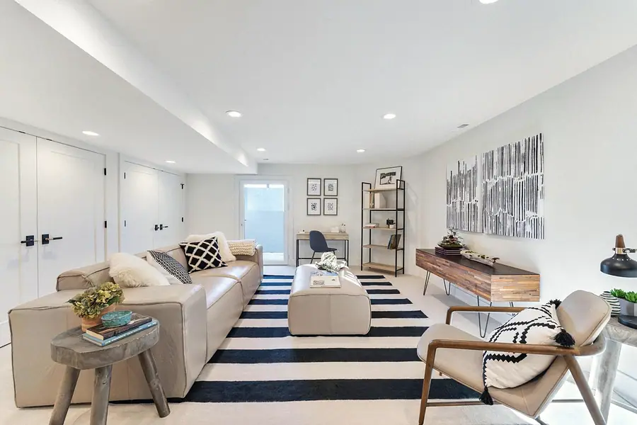 Lower-level living room with leather sectional, striped rug, and desk nook