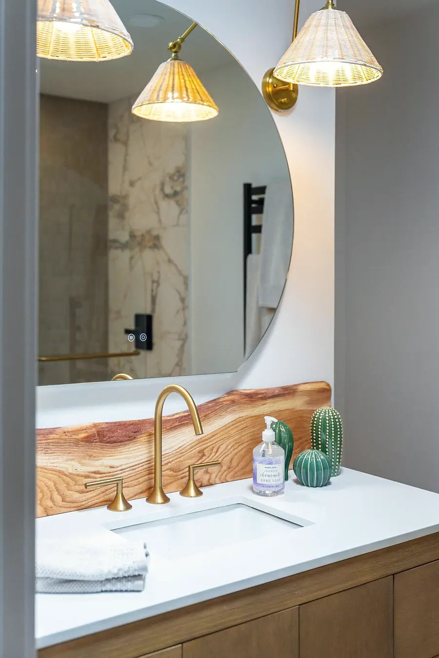 Little Gem vanity detail with brass fixtures, ceramic cacti, and round mirror