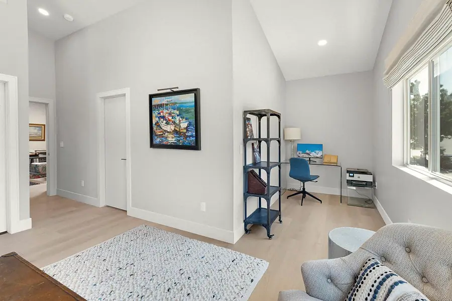 Elysium office alcove with glass desk, blue chair, and harbor painting