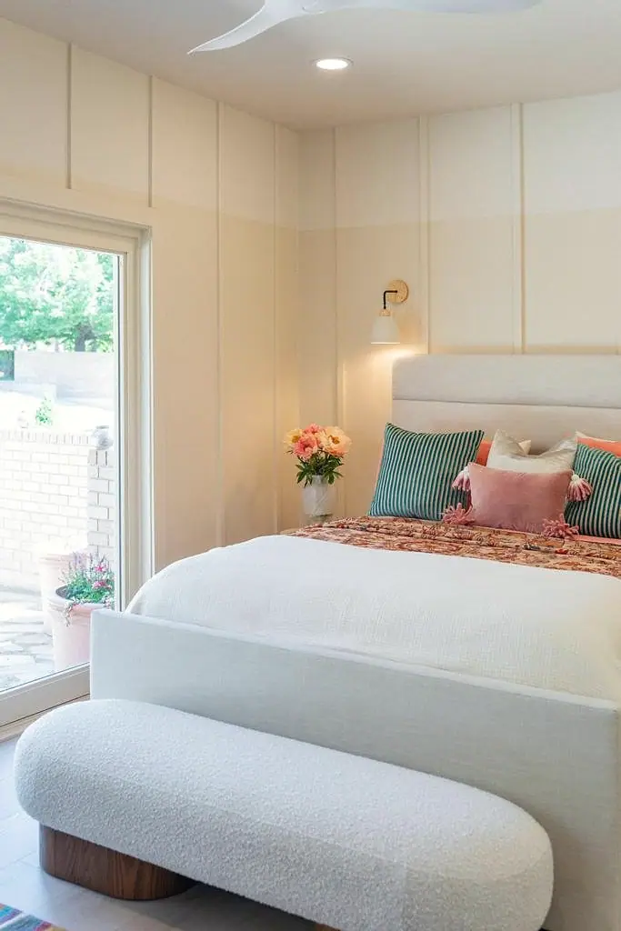 Crista da Montanha bedroom with cream paneled walls, bouclé bench, and garden patio doors