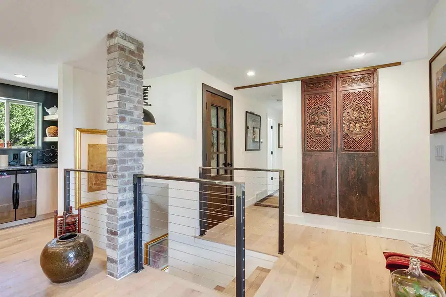 Wallace Project open hall with brick column, cable rail, and carved wood sliding doors