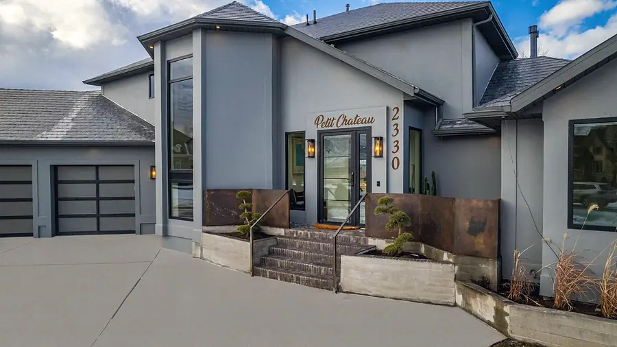 Main entrance of Le Petit Chateau with copper panels, bonsai planters, and house number 2330