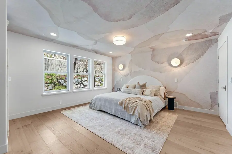 Grand Vista primary bedroom wide view with mural ceiling, oak floors, and soft rug