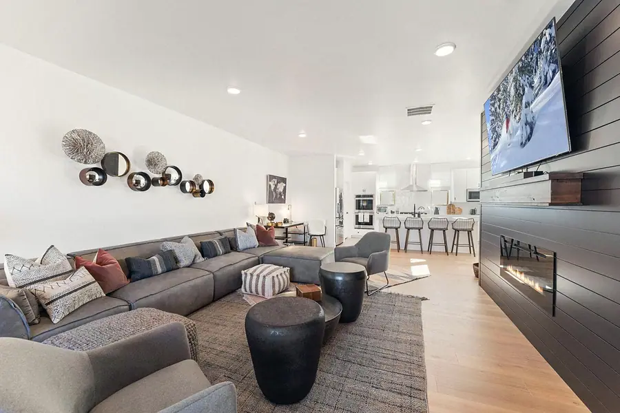 Silver Creek living room with gray sectional, fireplace TV wall, and open kitchen