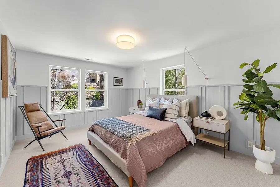 Grand Vista bedroom with leather lounge chair, blush bedding, and fiddle leaf fig