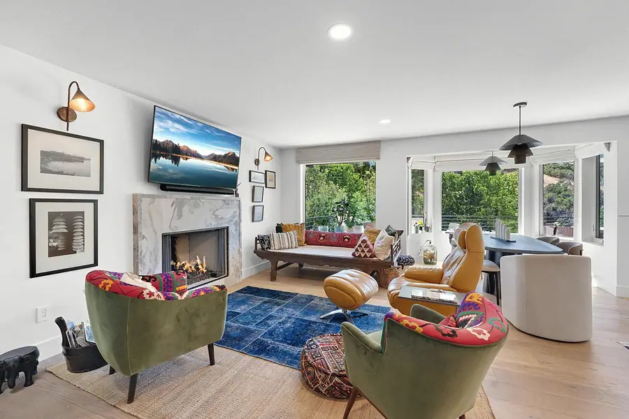 Elysium living room with marble fireplace, green embroidered chairs, and mustard leather recliner