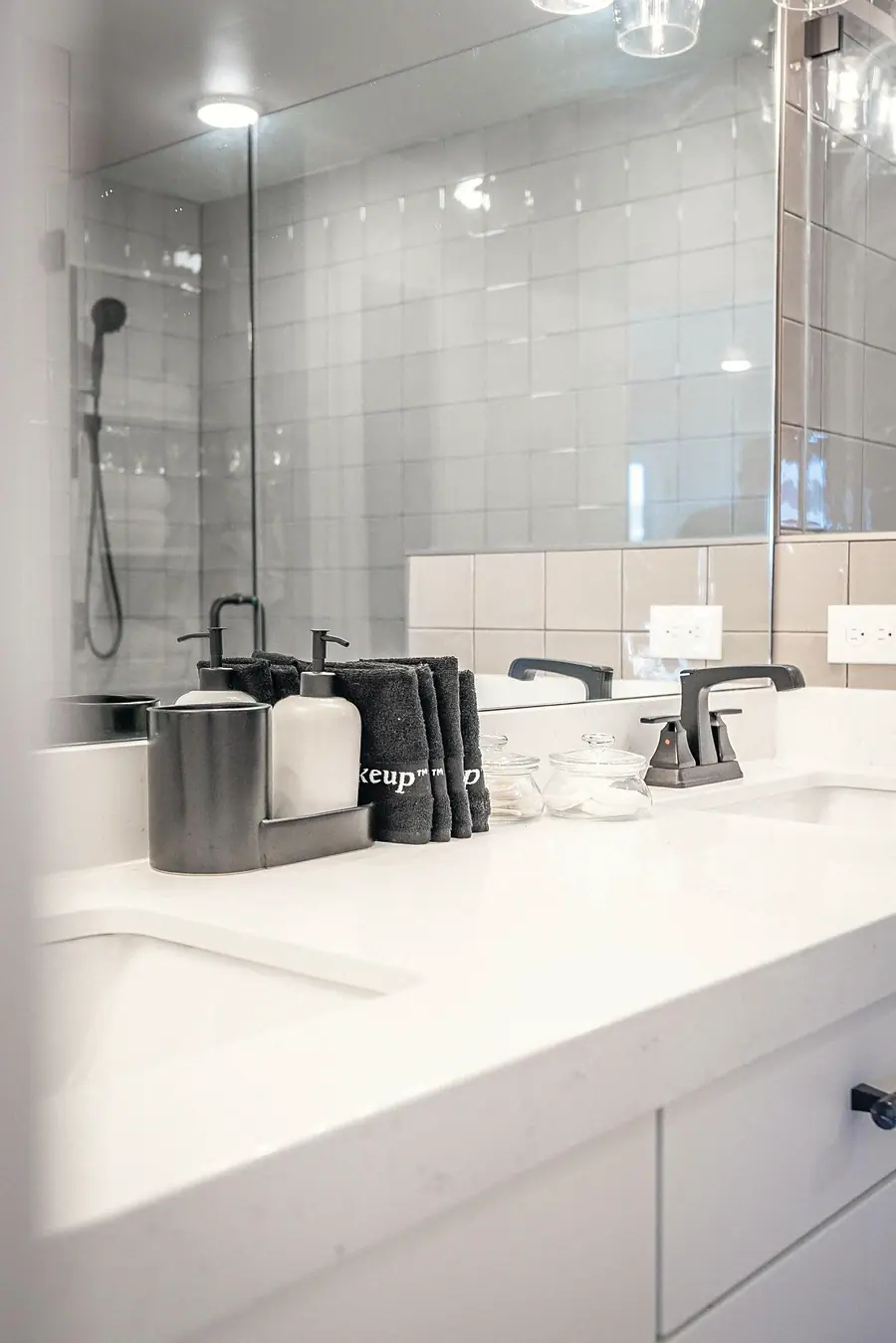 Silver Creek vanity detail with soap dispensers, black towels, and dual sinks