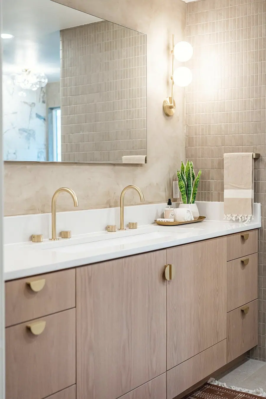 Grand Vista double vanity with brass faucets, light wood cabinets, and wall sconces